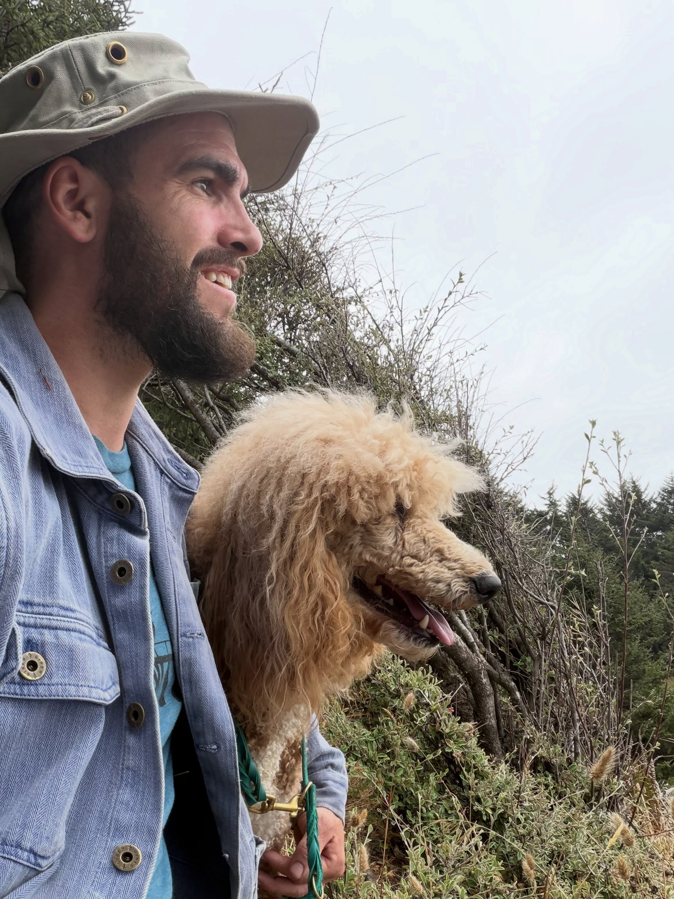 Philip smiling while holding his standard poodle outdoors